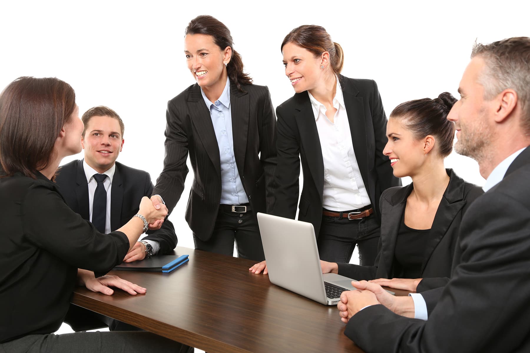 Team im Gespräch an einem Besprechungstisch mit Notebook
